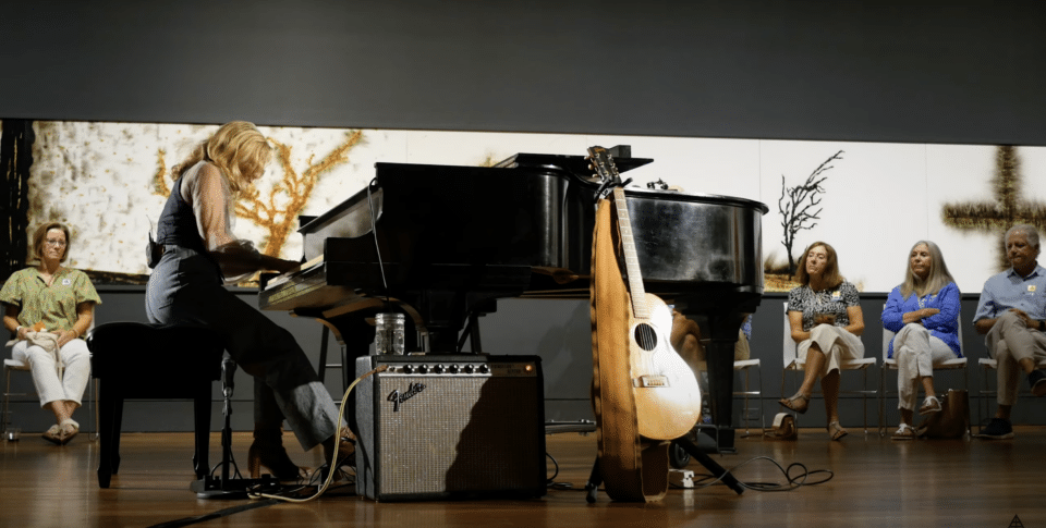 Tift Merritt playing piano and singing inside art exhibit.